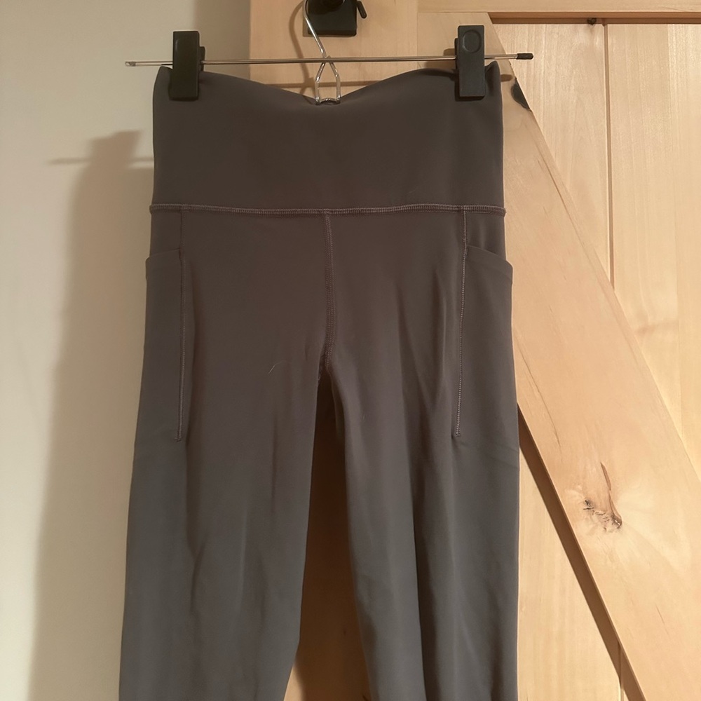 Olive green (gray/green) Athleta salutation leggings with stash pockets.